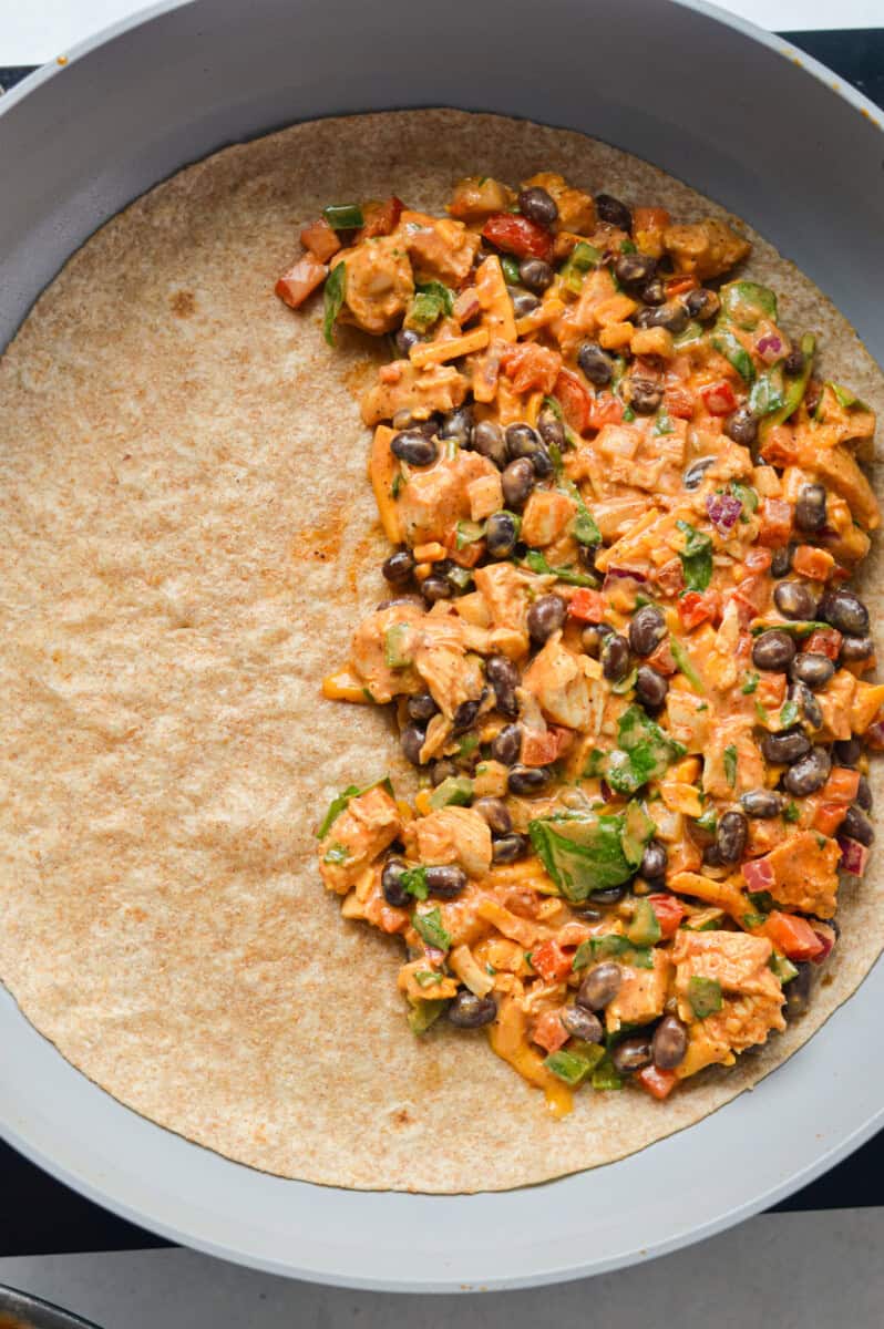 Adding filling to half the tortilla.