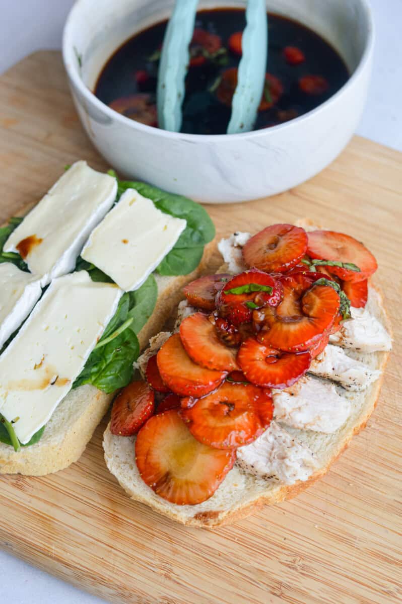 Assembling balsamic strawberry and chicken sandwich with spinach and brie.