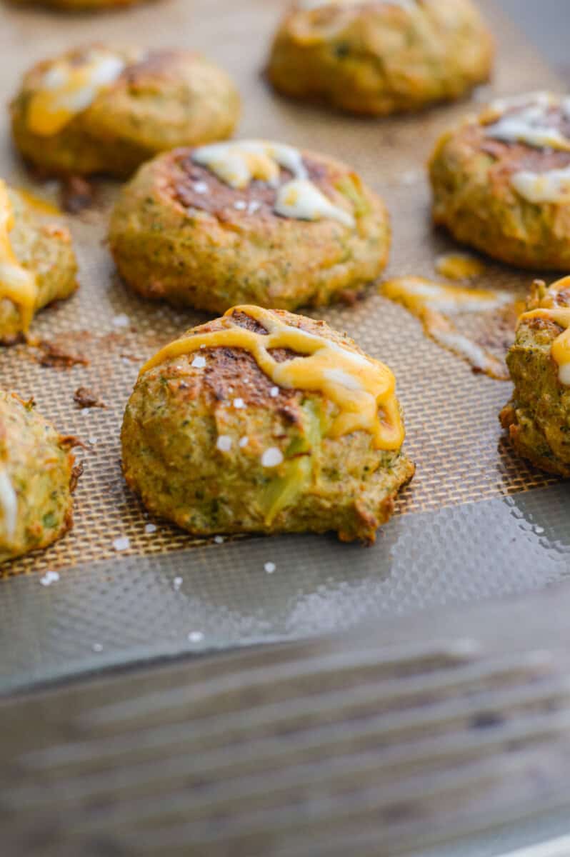 Adding extra shredded cheese onto baked broccoli bites.