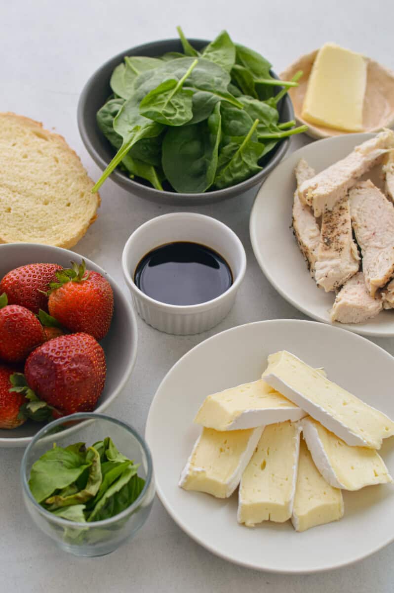 Ingredients including brie, bread, balsamic, strawberries, basil, spinach and chicken.