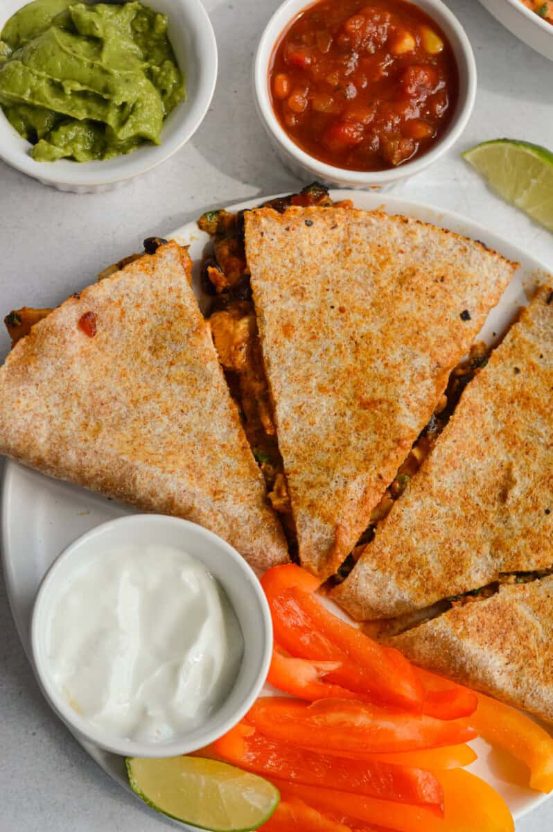 Birds eye of a plate with bbq chicken quesadilla, served with veggies and dip.