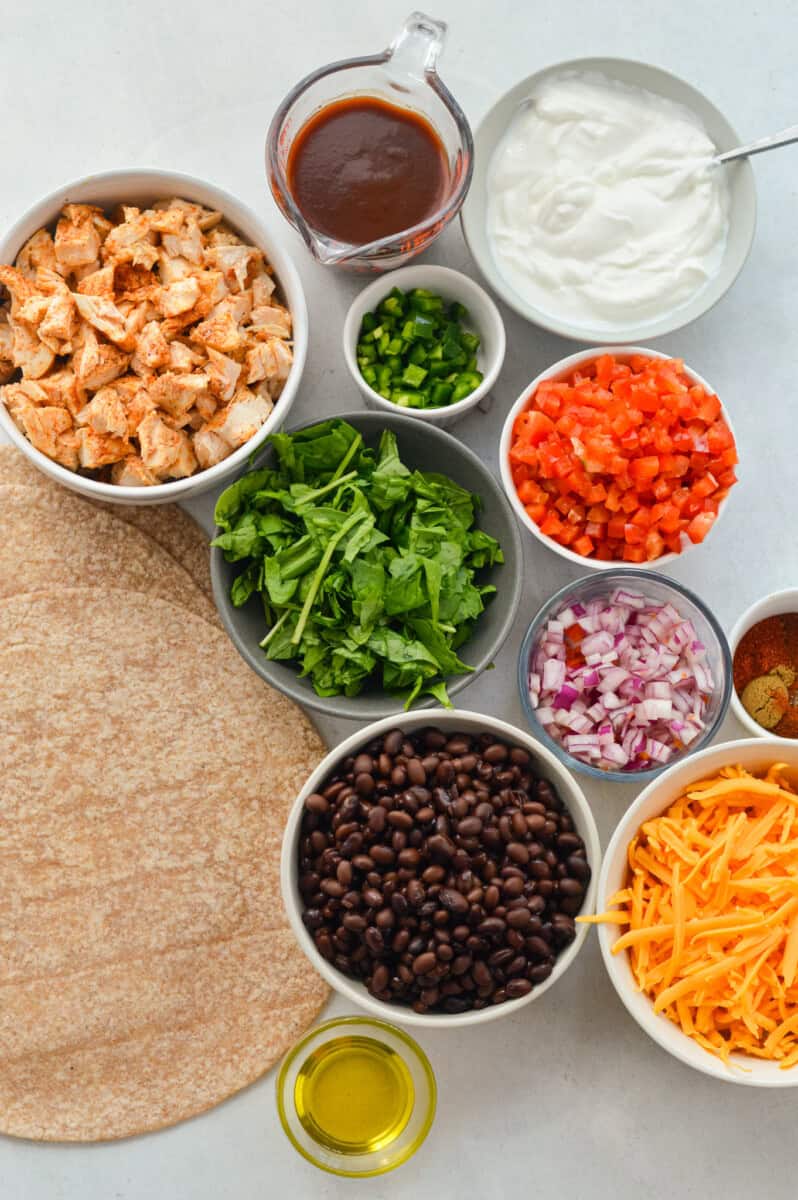 Ingredients including tortilla, black beans, cheese, red onion, jalapeno, spinach, red onion, greek yogurt and BBQ sauce.