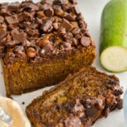 Loaf of chocolate chip zucchini loaf with a slice cut.