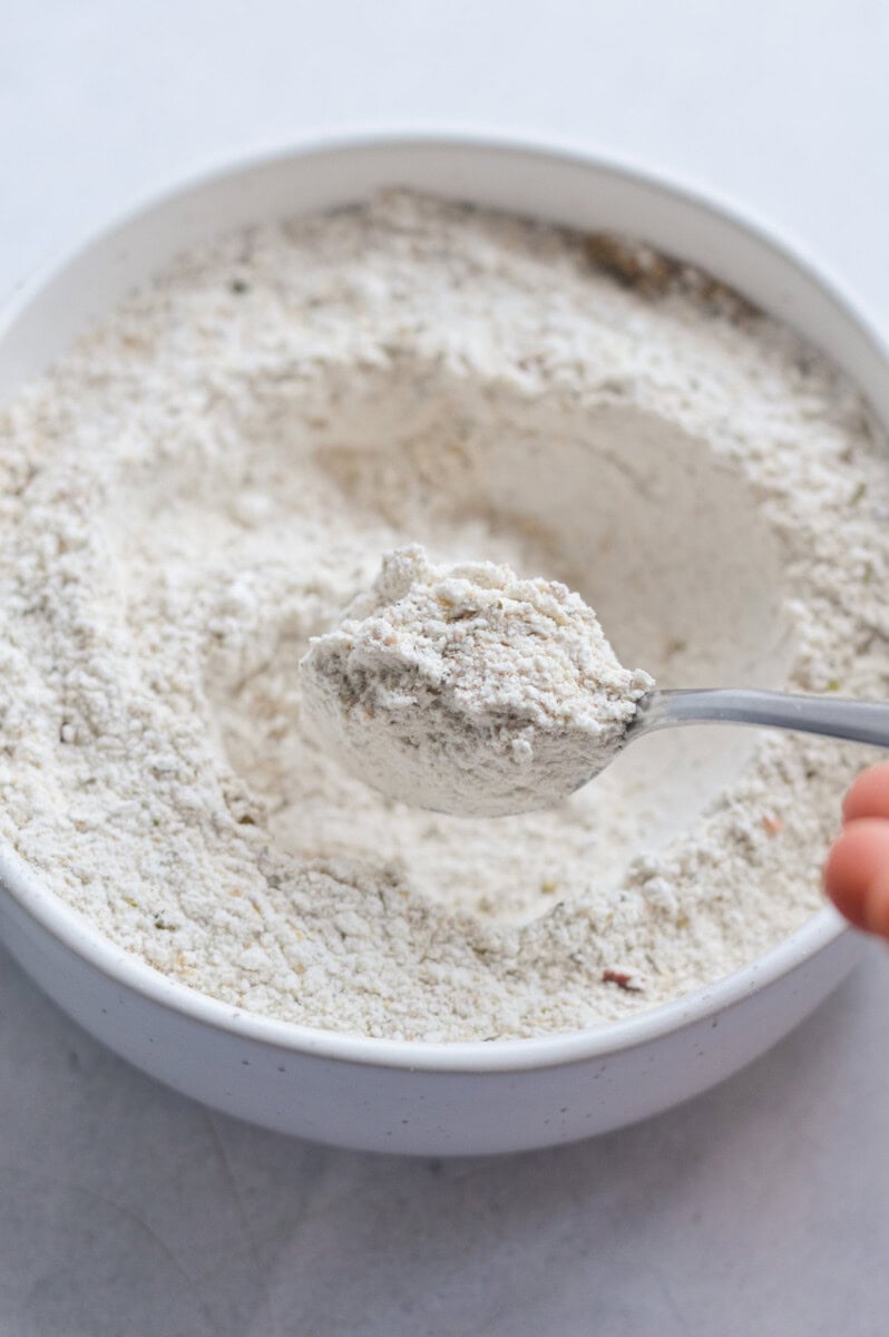 Mixing together flour, baking powder, ground flax seed, Italian seasoning, onion powder, salt and black pepper.
