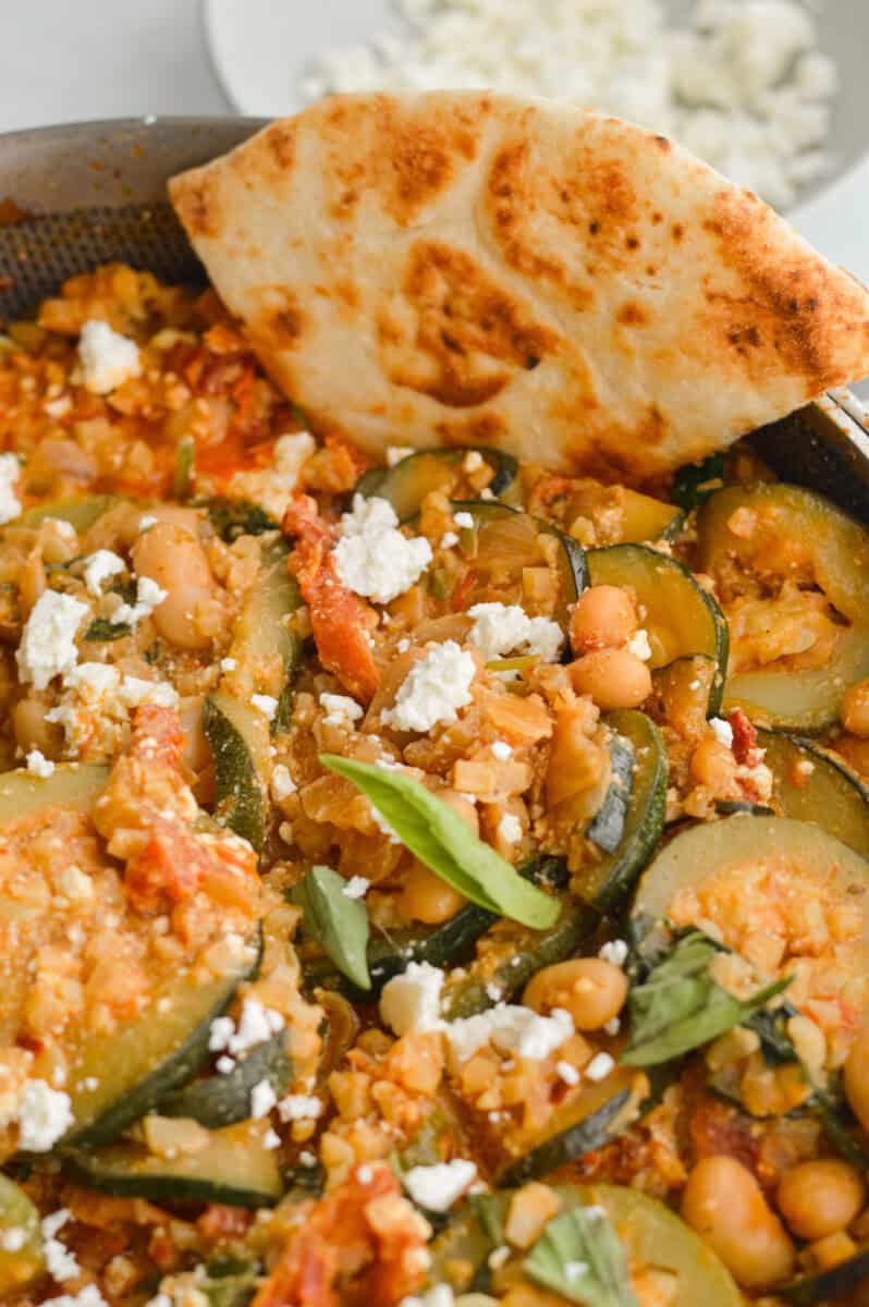 Close up of cheesy white bean tomato bake with pita.