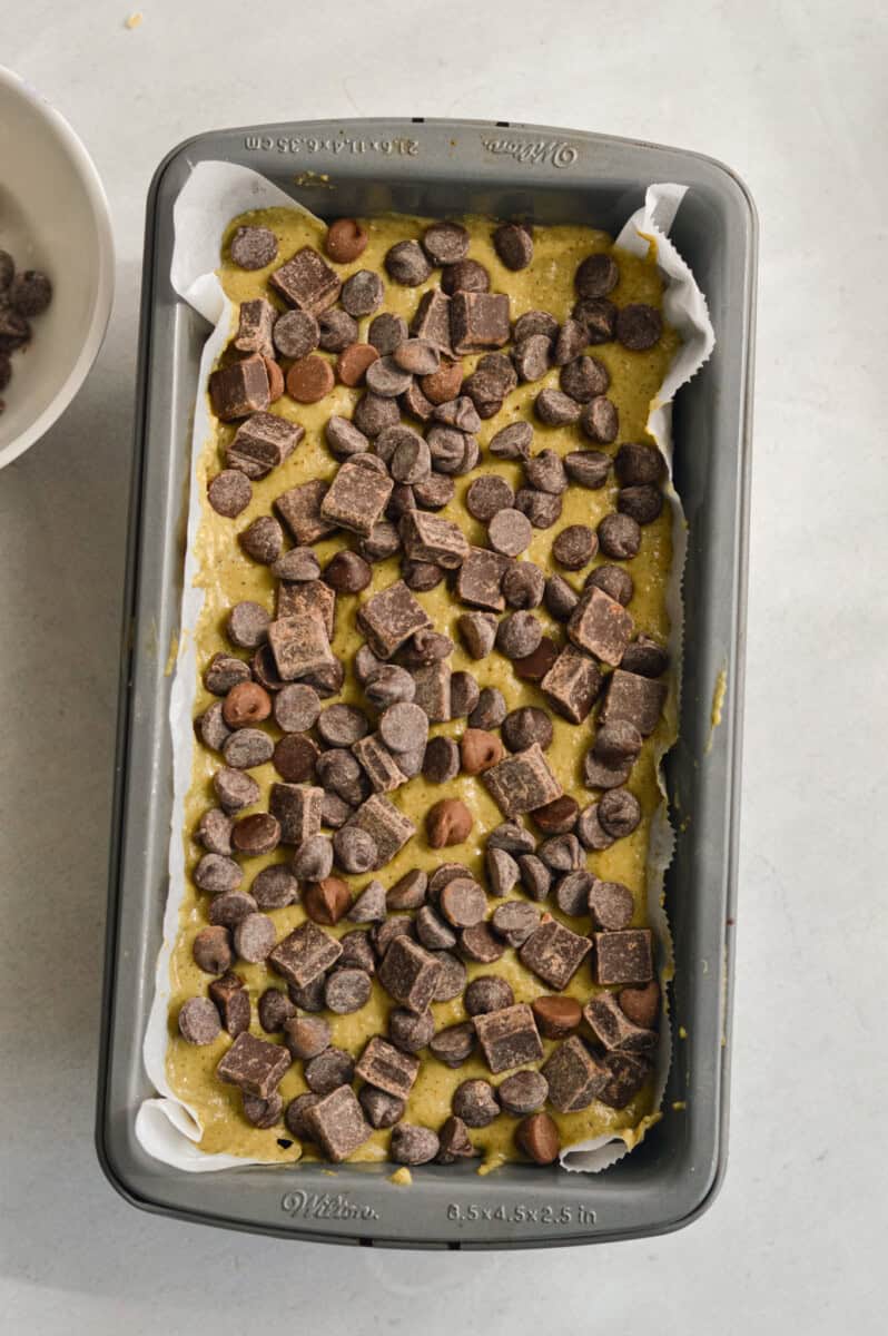 Zucchini batter in  loaf pan with chocolate chips sprinkled on top.