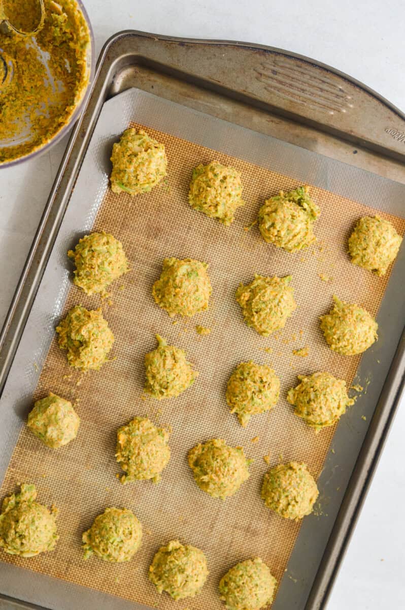 Scooping broccoli bite batter onto a baking tray.