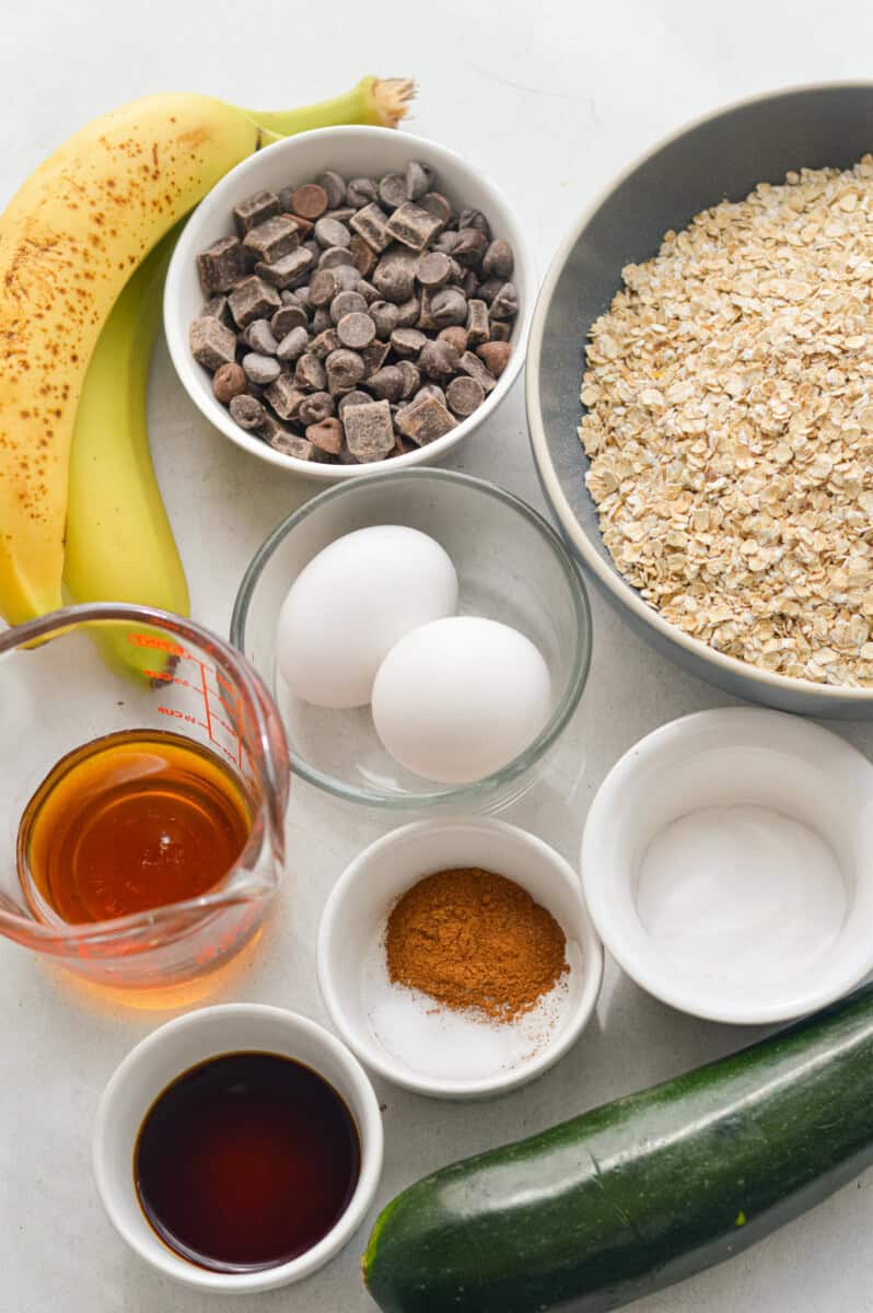Ingredients including bananas, eggs, oats, chocolate chips, maple syrup, seasoning.