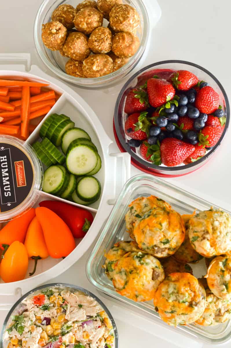 Birds eye of week 12 meal prep recipes, including a veggie tray, berries, savory muffins and chicken salad.