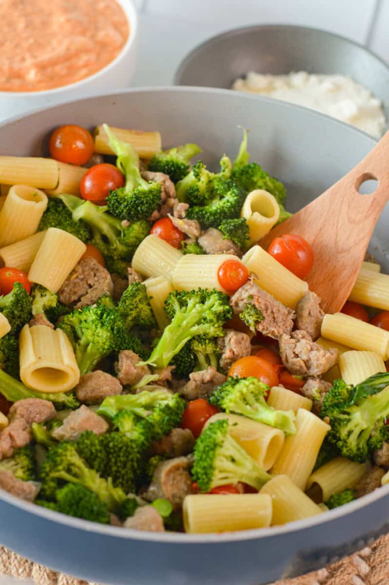 Cooking pasta, sausage and vegetables in a pan.
