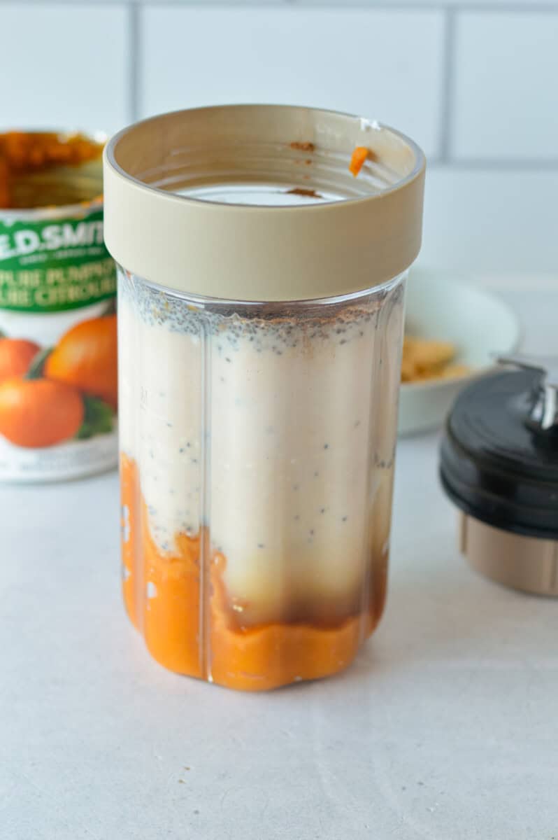  A blender filled with milk, pumpkin puree, maple syrup, vanilla extract, greek yogurt, chia seeds, pumpkin pie spice and salt.