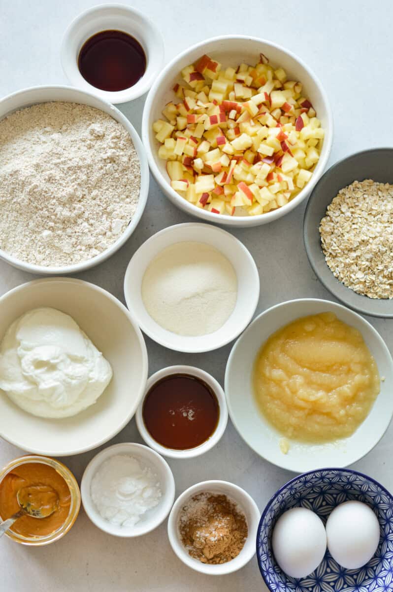 Ingredients including apples, applesauce, oat flour, eggs, Greek yogurt, maple syrup, collagen, spices, baking powder and peanut butter.