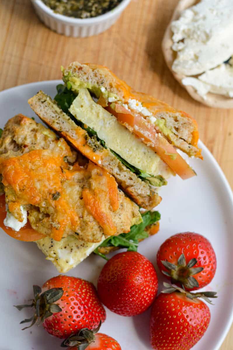 Bagel breakfast sandwich on a plate with strawberries.