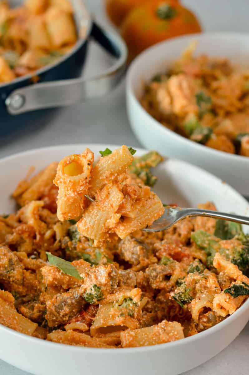 Serving a bowl of pasta with sausage and broccoli.