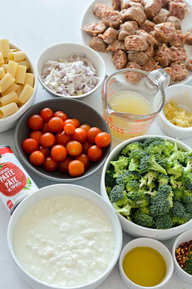 Ingredients including chicken sausage, cherry tomatoes, broccoli, cottage cheese, chicken broth, rigatoni, olive oil, garlic and spices.