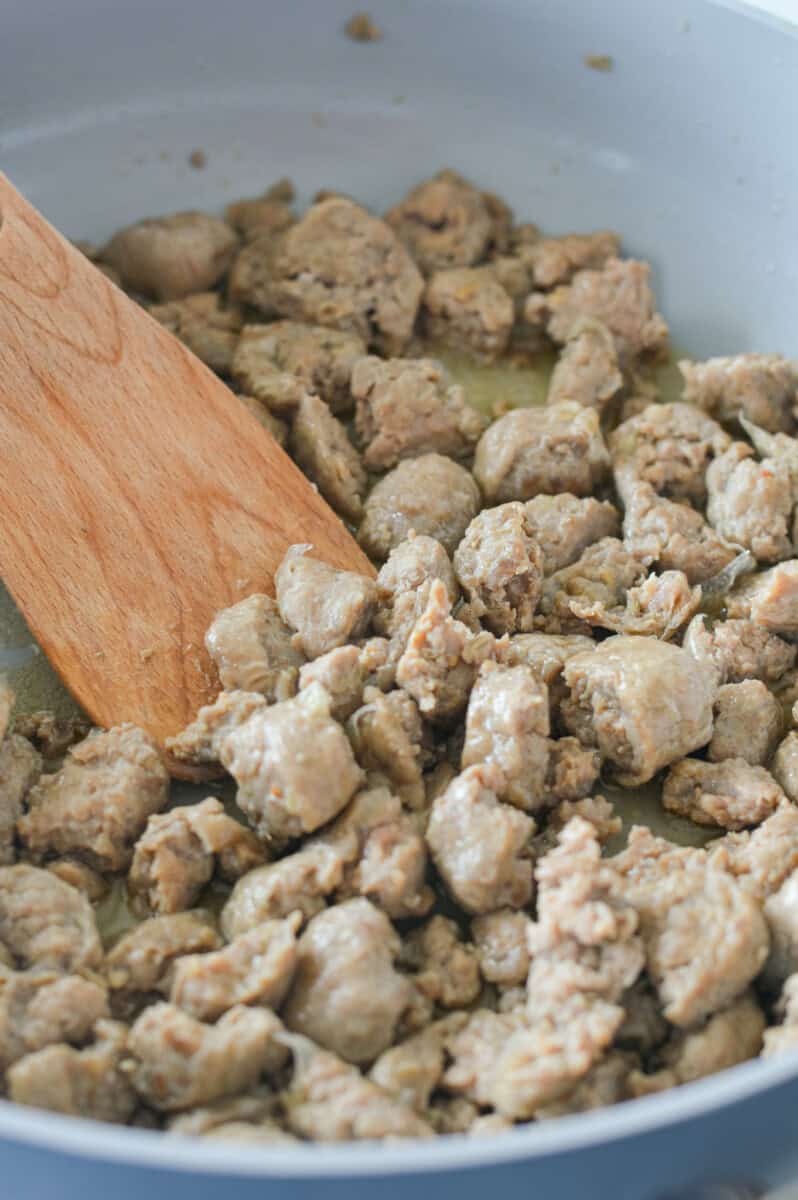 Cooking sliced chicken sausage in a pan.