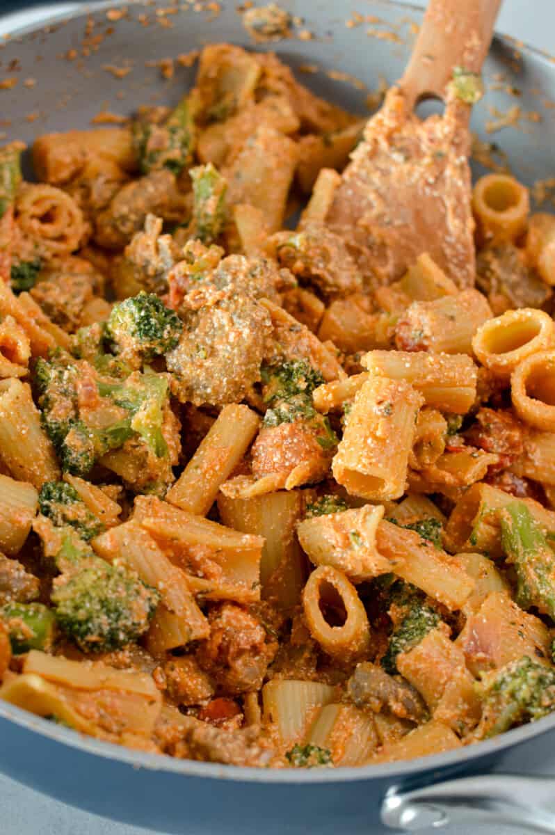 Cooking pasta with sausage and broccoli in a pan.