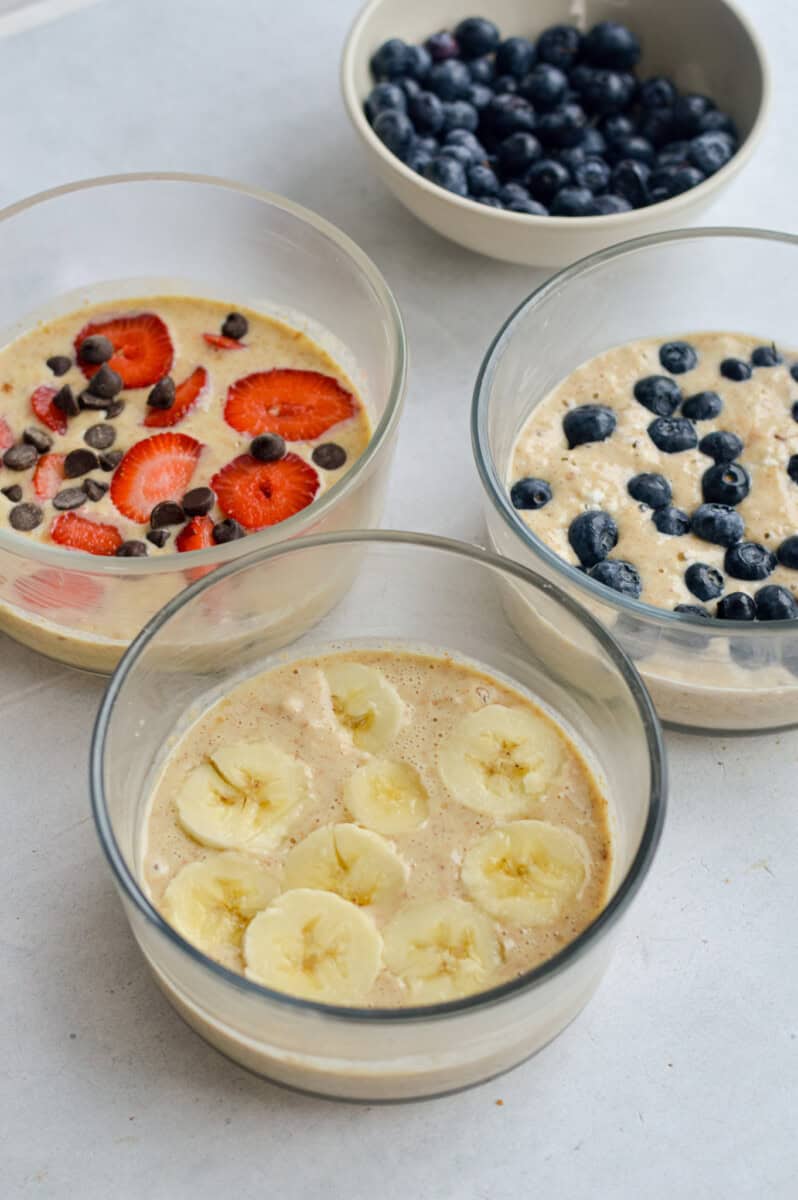 Topping pancake bowls with berries and banana slices.