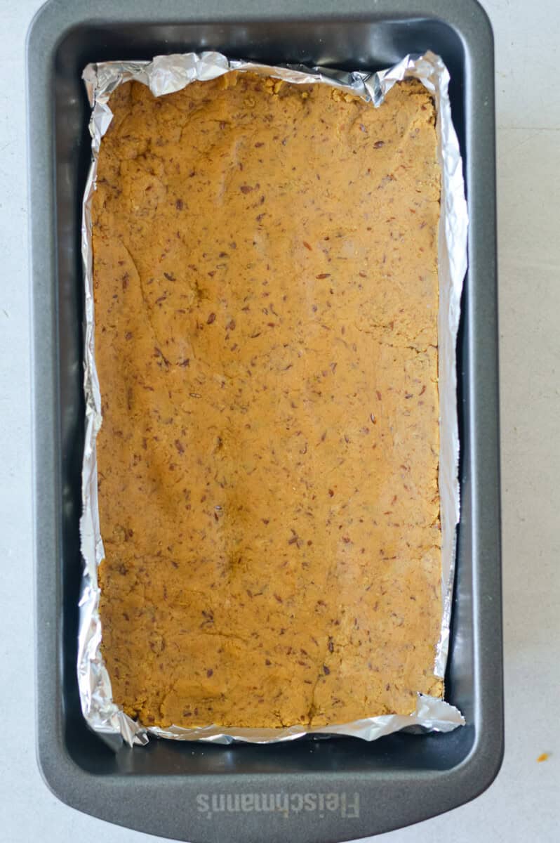 Pressing protein bar base into a loaf pan.