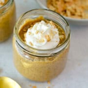Jar of pumpkin chia pudding topped with whipped cream.