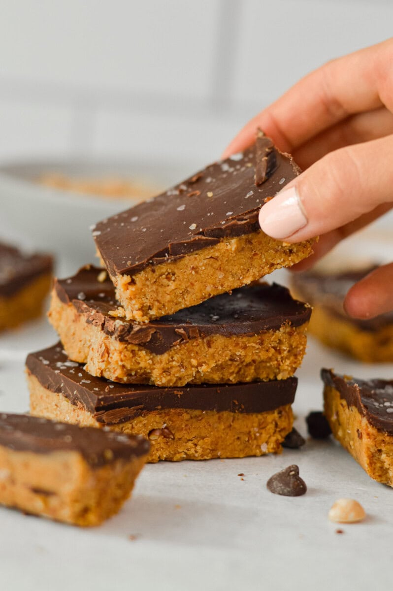 Taking a chocolate peanut butter protein bar off a stack.