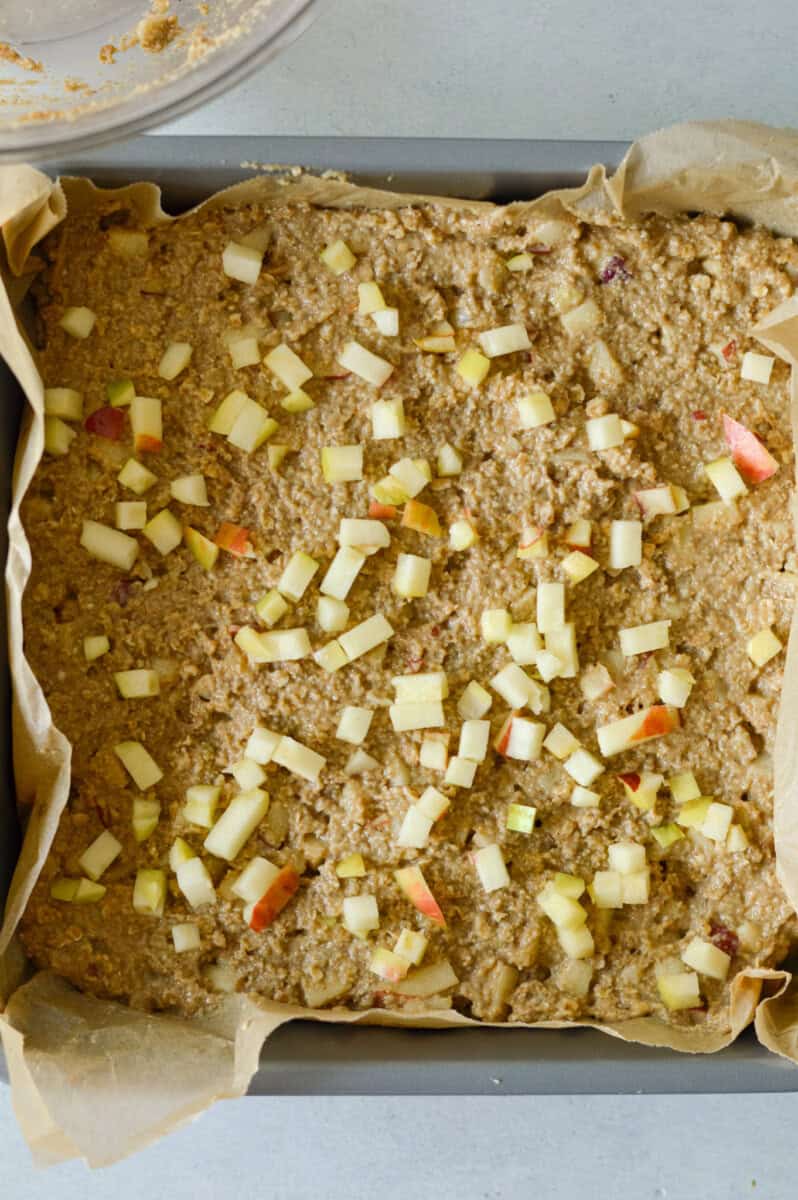 Spreading apple oat bar batter in a square baking dish.