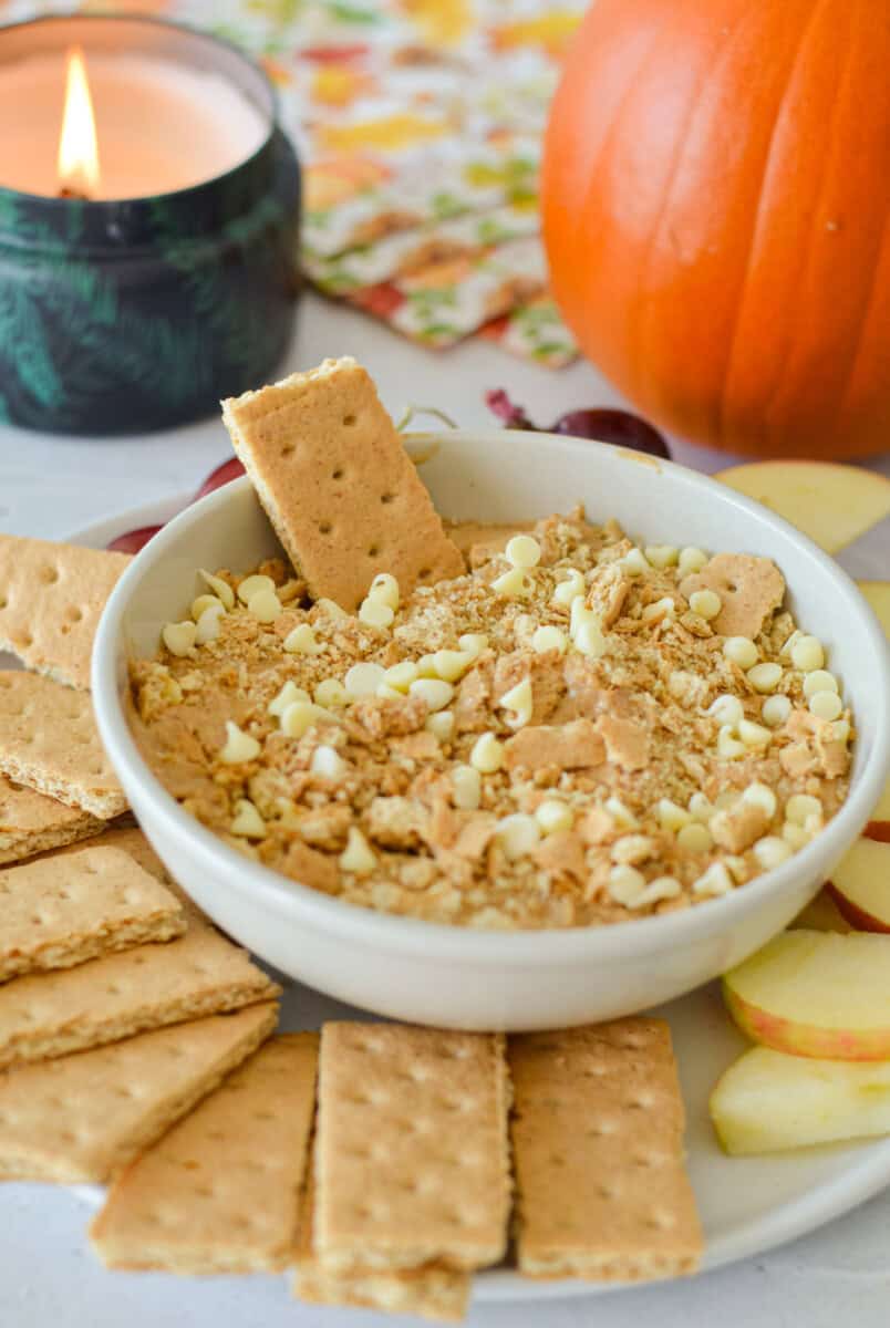 Bowl of pumpkin pie cream cheese dip served with graham crackers and apple slices.