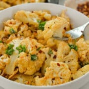 Bowl of oven roasted cauliflower with tahini sauce.
