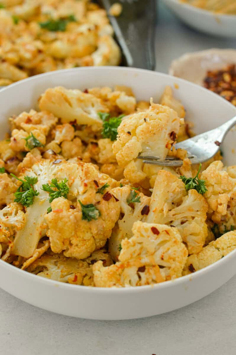Bowl of oven roasted cauliflower with tahini sauce.