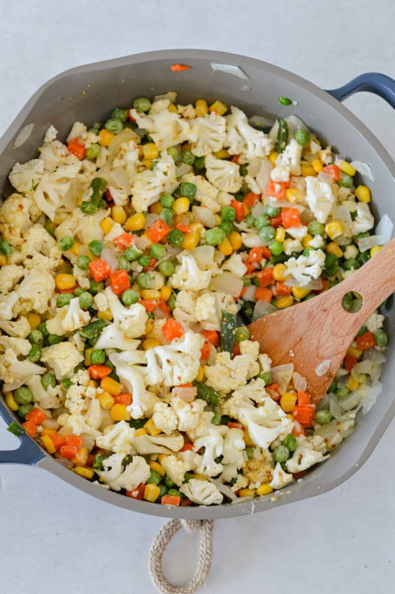 Cooking mixed veggies and cauliflower in a pan.