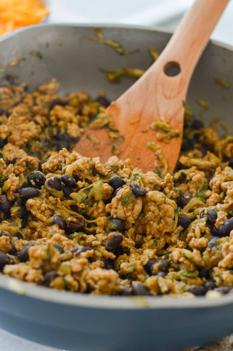 Cooking ground chicken, zucchini and other spices in a pan.