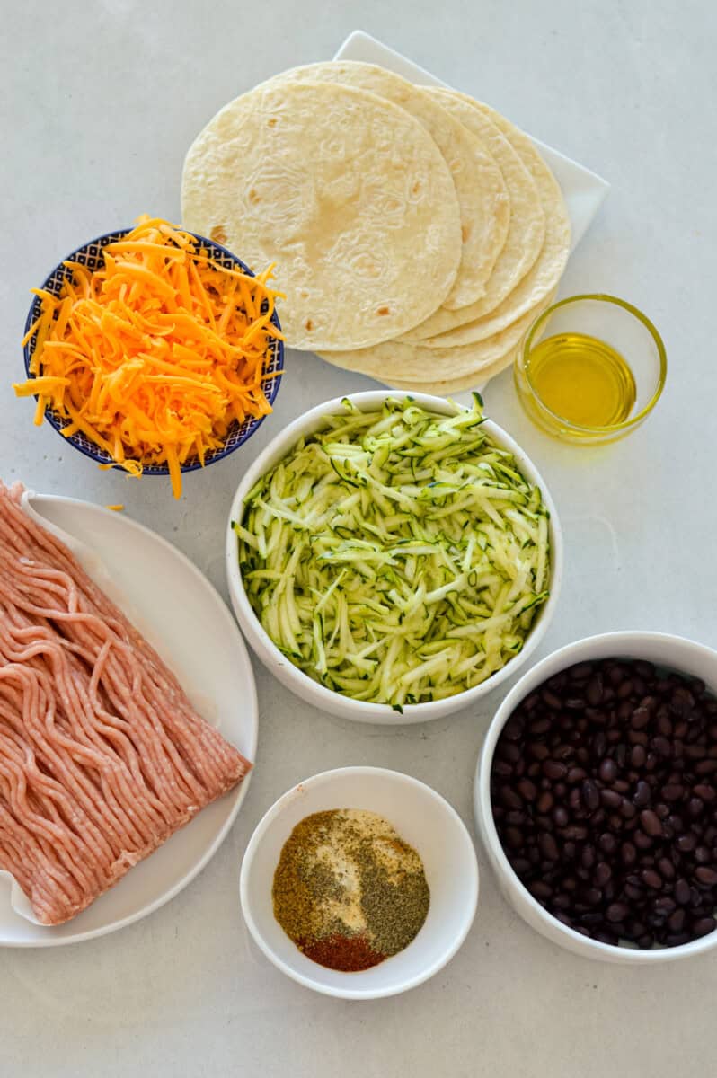 Ingredients including ground chicken, shredded carrot and zucchini, spices, tortilla and olive oil.