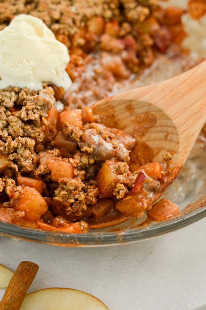 Close up of healthy apple crumble recipe with a wooden serving spoon.