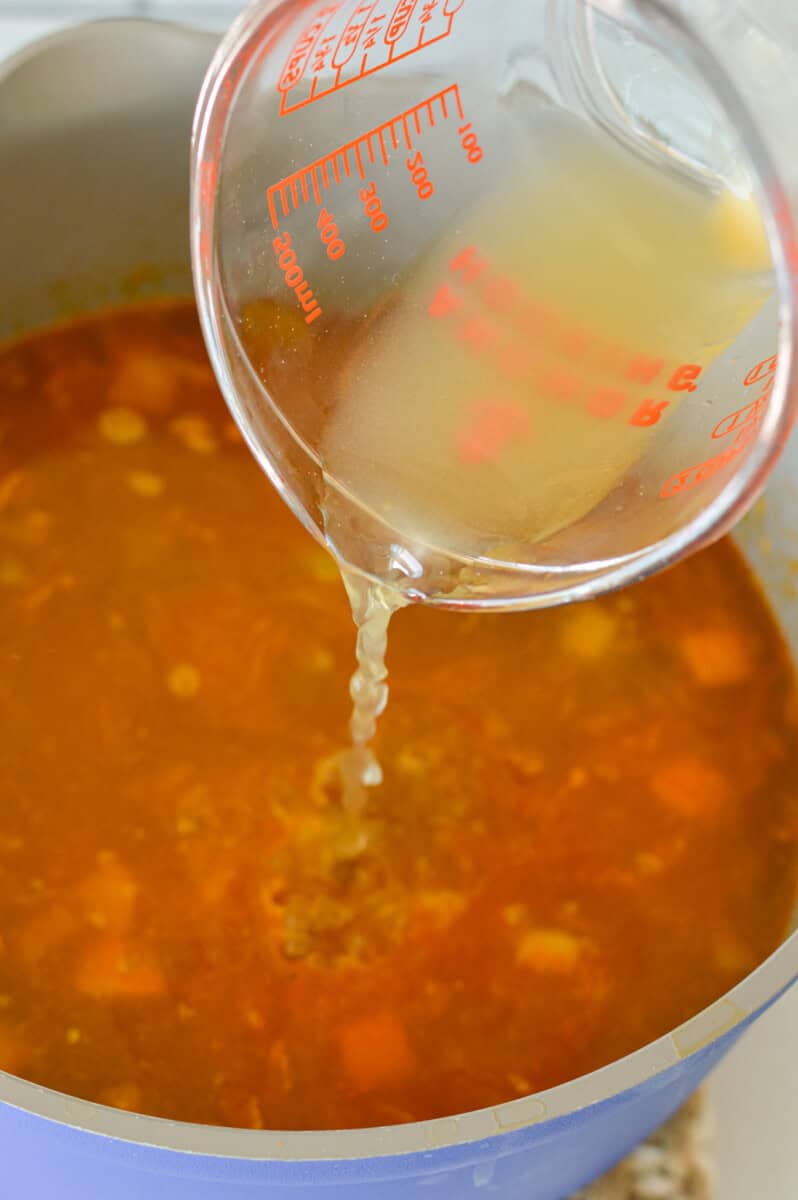 Pouring bone broth into chicken soup.