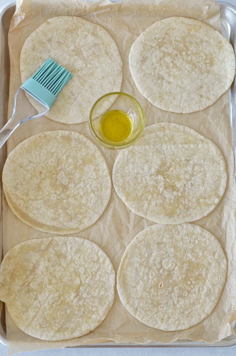 Brushing flour tortillas with olive oil.