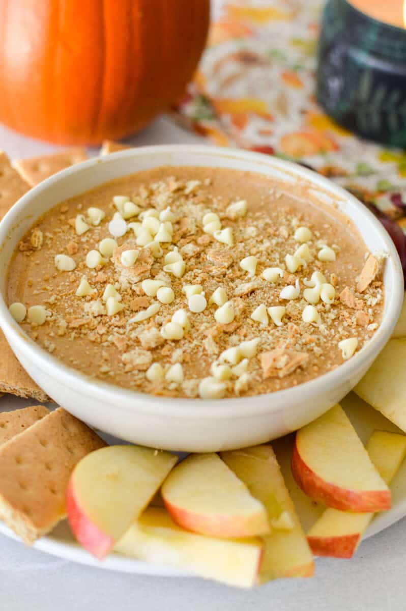 Bowl of pumpkin pie cream cheese dip topped with mini white chocolate chips.