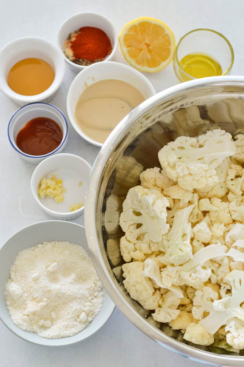 Ingredients including cauliflower florets, tahini, parmesan, seasoning, olive oil, honey, Greek yogurt, and sriracha.
