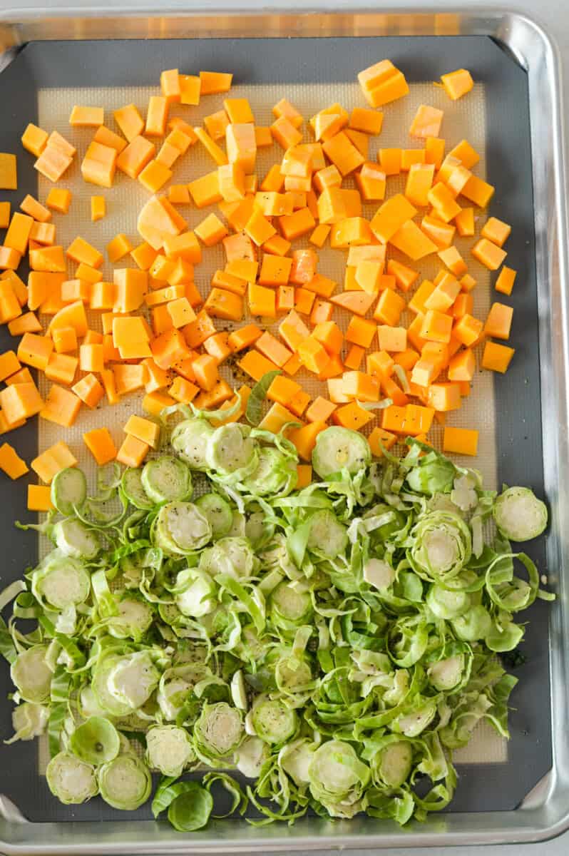 Sheet pan with diced butternut squash and shredded brussels sprouts.