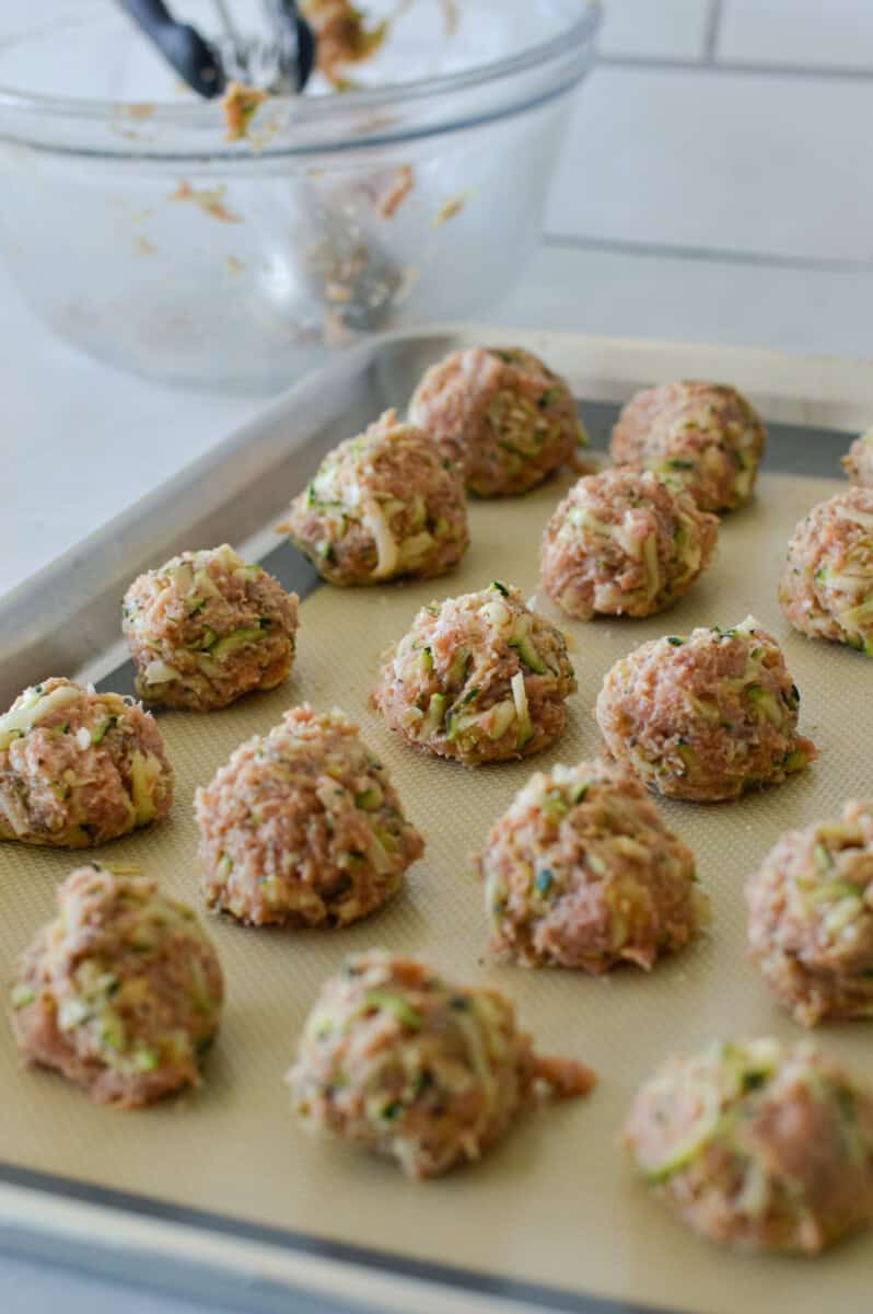 Rolling meatballs out on a tray.
