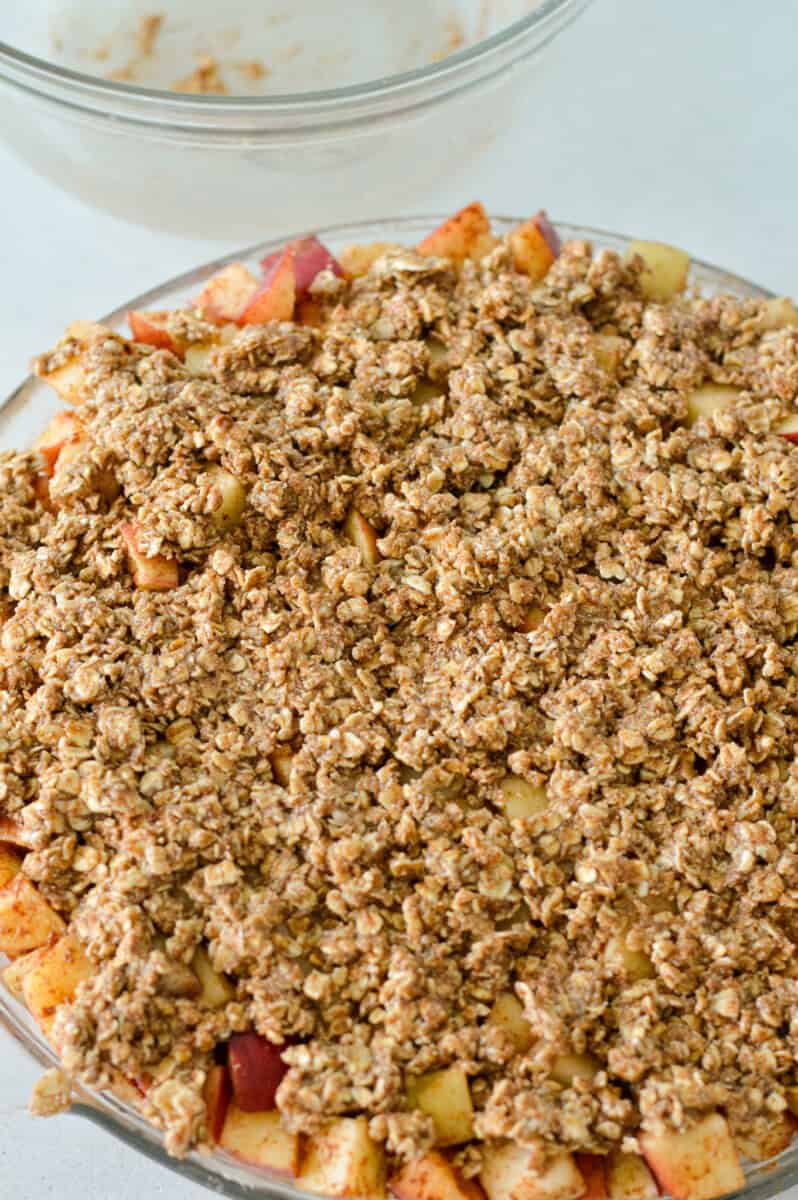 Pressing oat crumble on top of diced apples.