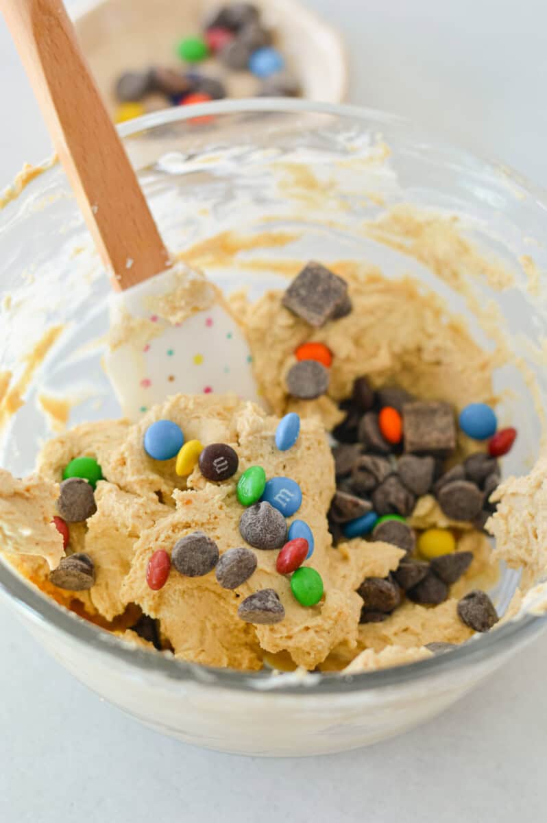Mixing chocolate chips and M&Ms into protein cookie dough.