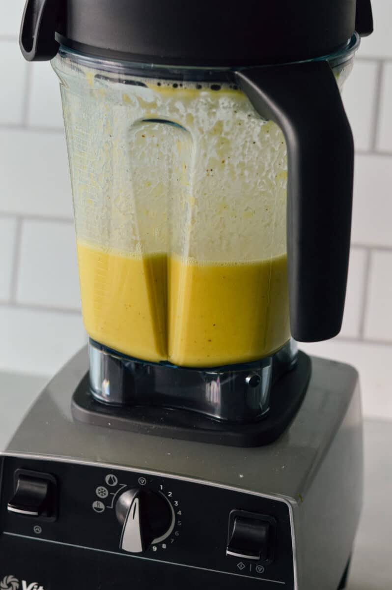 Blending lemon juice, water, olive oil, peeled oranges, chopped ginger, turmeric and black pepper in a blender.