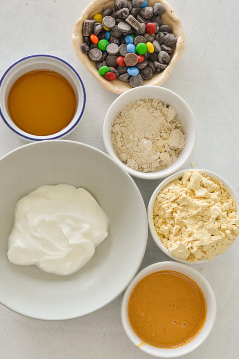 Ingredients including Greek yogurt, oat flour, peanut butter, protein powder, chocolate chips, vanilla, and maple syrup.