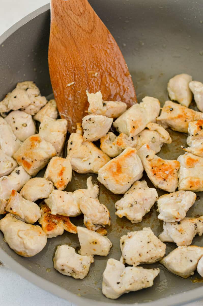 Cooking cubed chicken breast in a pan.