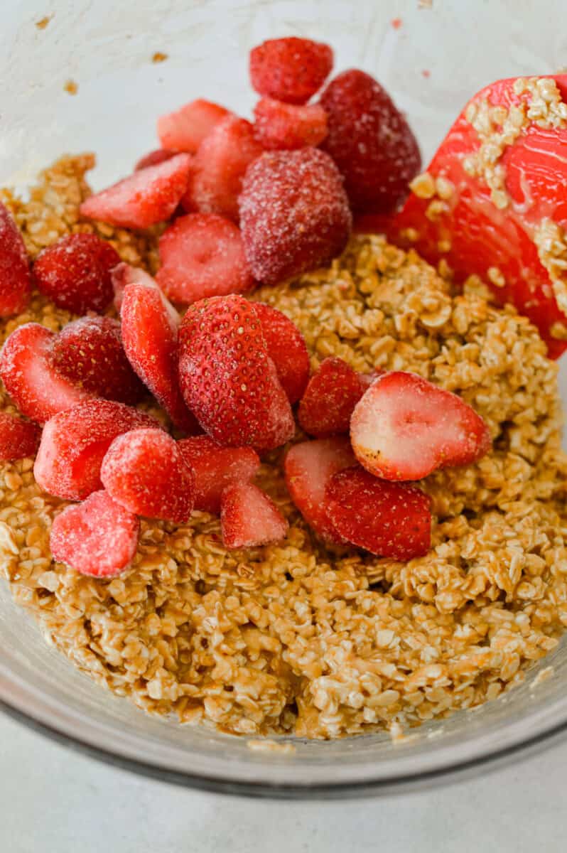 Mixing strawberries and oats into the bowl.