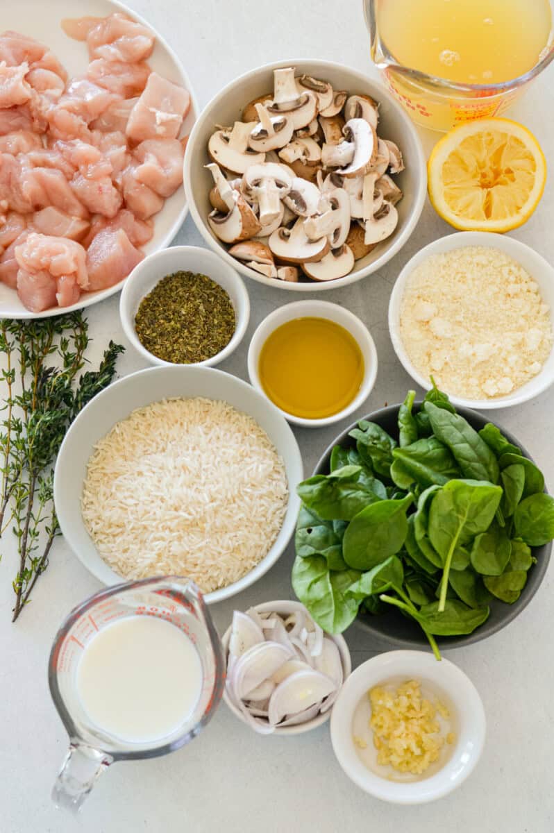 Ingredients including chicken breast, rice, spinch, parmesan, spices, broth, lemon and milk.