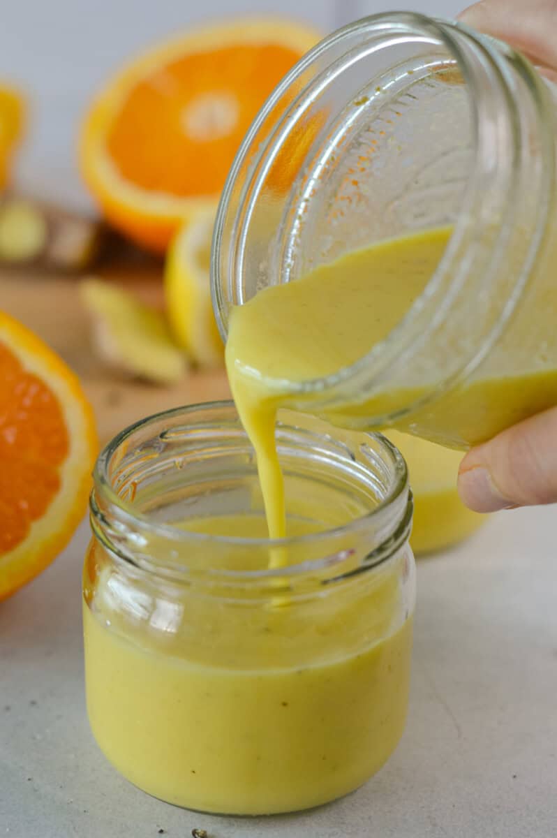 Pouring ginger shots into a glass jar.