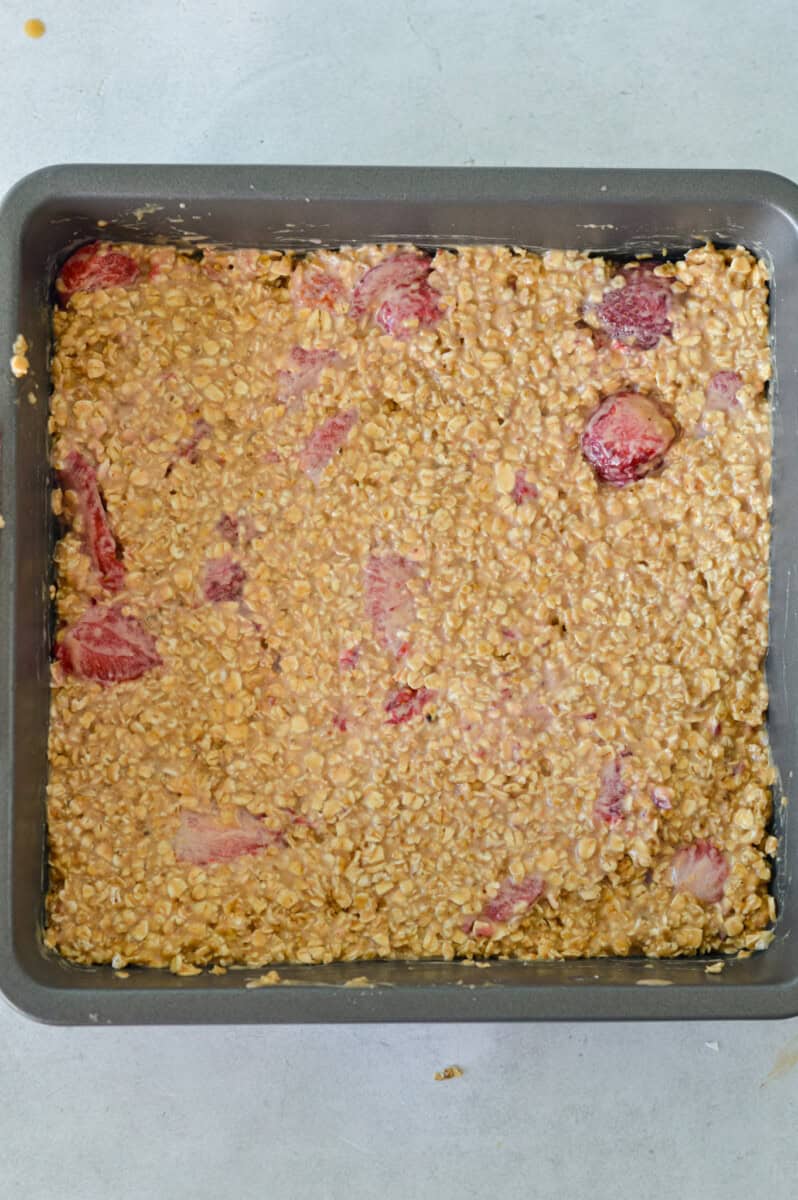 Pressing strawberry oat mixture in a pan.