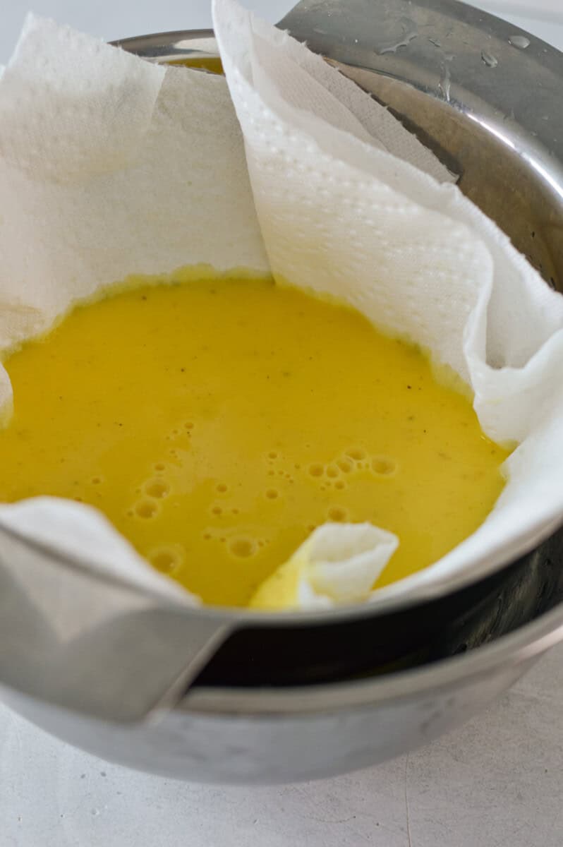 Straining ginger shots through a cheesecloth.