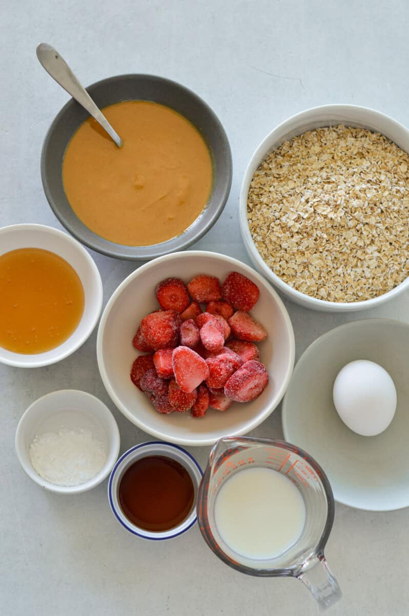 Ingredients including oats, egg, strawberries, peanut butter, honey, milk, baking powder and vanilla.